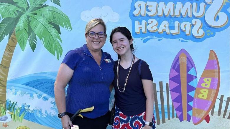 Two women standing in front of a Sesame Place sign